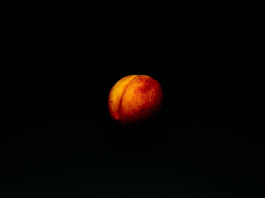 a ripe peach against a black background
